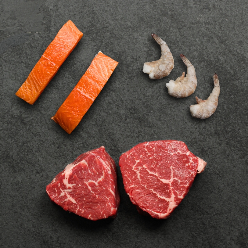 overhead image of shrimp, salmon, and steak