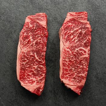 overhead view of two raw, heavily marbled Australian wagyu beef New York steaks