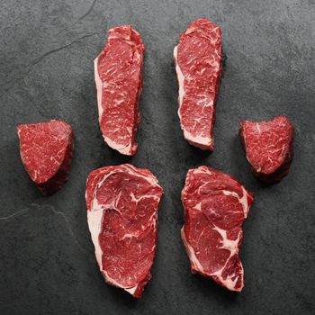 overhead view of 2 raw rib eyes, 2 raw new york steaks, and 2 raw filet mignon's