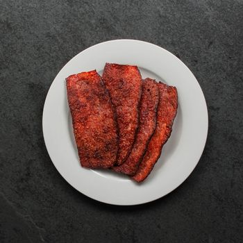 overhead view of a white plate with a few pieces of crispy turkey bacon on top