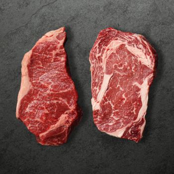 overhead view of a raw New York steak and a raw rib eye steak
