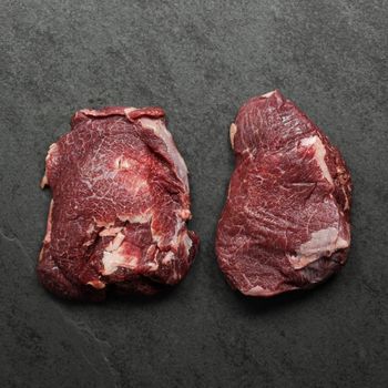overhead view of two raw, richly-marbled beef cheeks