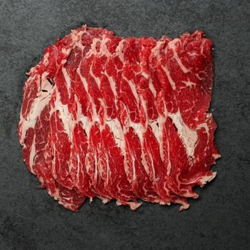 overhead view of very thin slices of raw, shaved rib eye meat
