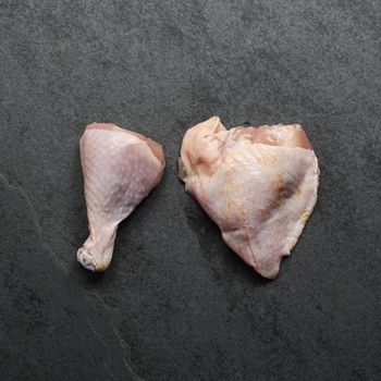 overhead view of a raw chicken drumstick and bone-in skin-on thigh