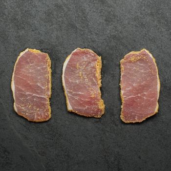 overhead view of three thinly sliced pieces of raw peameal bacon