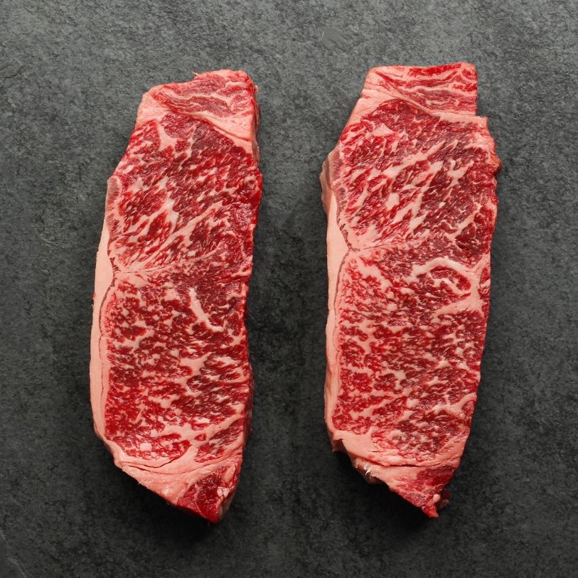 overhead view of two raw, heavily marbled Australian wagyu beef New York steaks