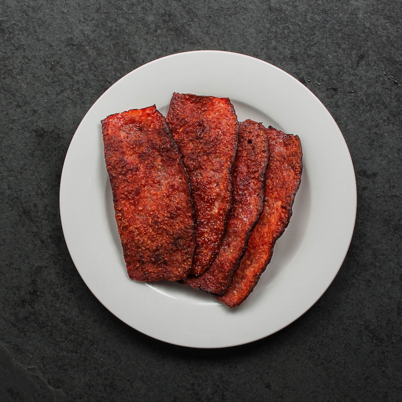 overhead view of a white plate with a few pieces of crispy turkey bacon on top