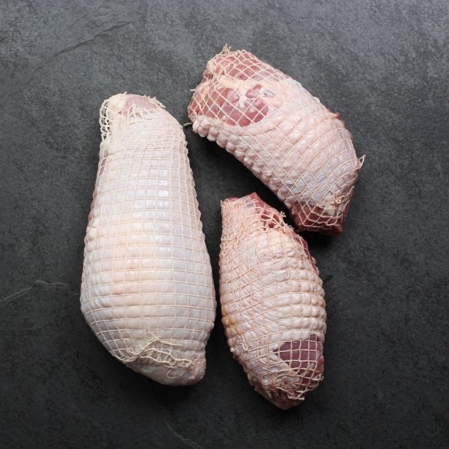 overhead view of a raw netted turkey breast and two raw netted turkey thighs