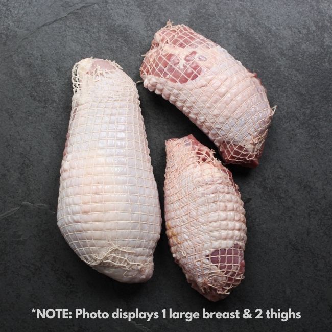 overhead view of a raw netted turkey breast and two raw netted turkey thighs