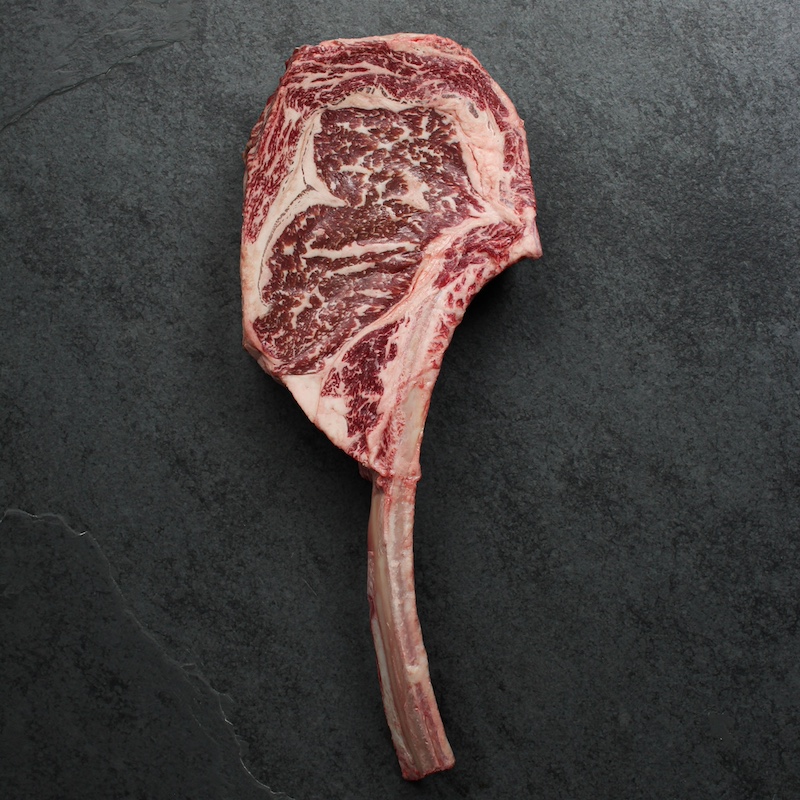 overhead view of a raw, richly-marbled wagyu beef tomahawk steak