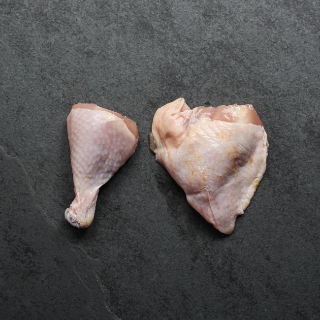 overhead view of a raw chicken drumstick and bone-in skin-on thigh