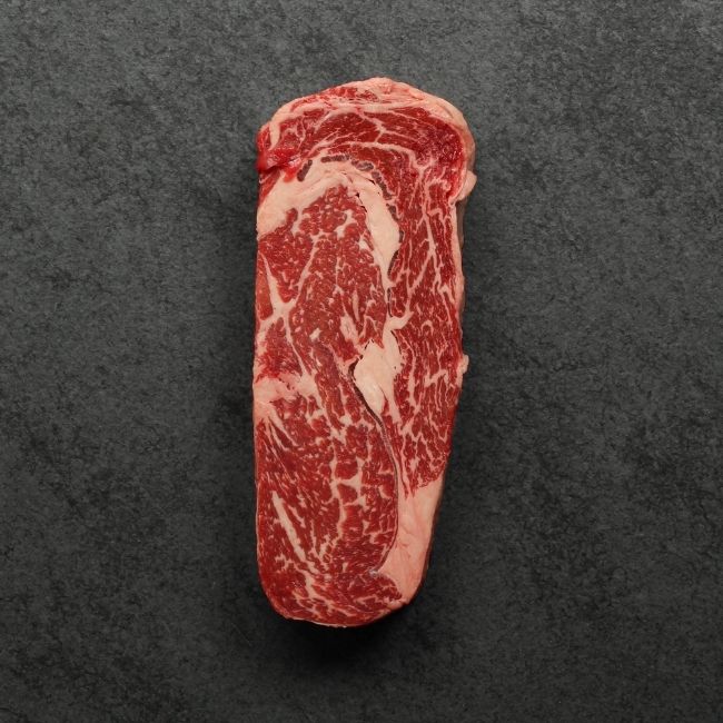 overhead view of a raw, well-marbled grass fed ribeye steak