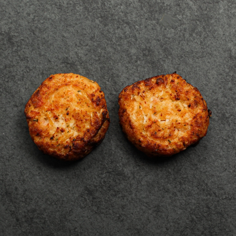 Overhead image of two cooked Lobster & Seafood cakes on a slate.