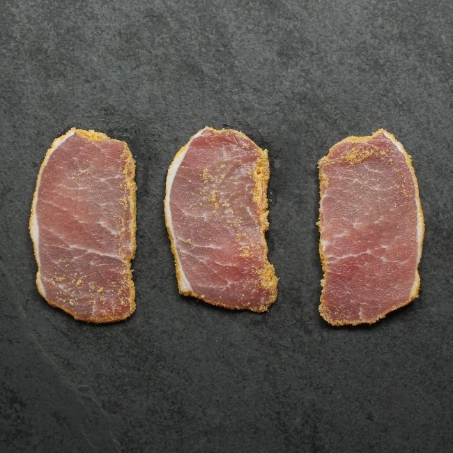 overhead view of three thinly sliced pieces of raw peameal bacon