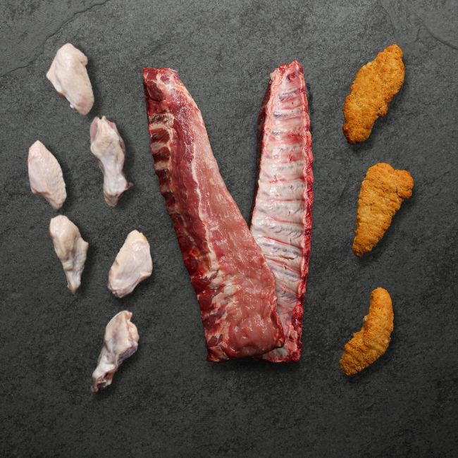 overhead image of raw chicken wings, pork back ribs and breaded chicken fingers