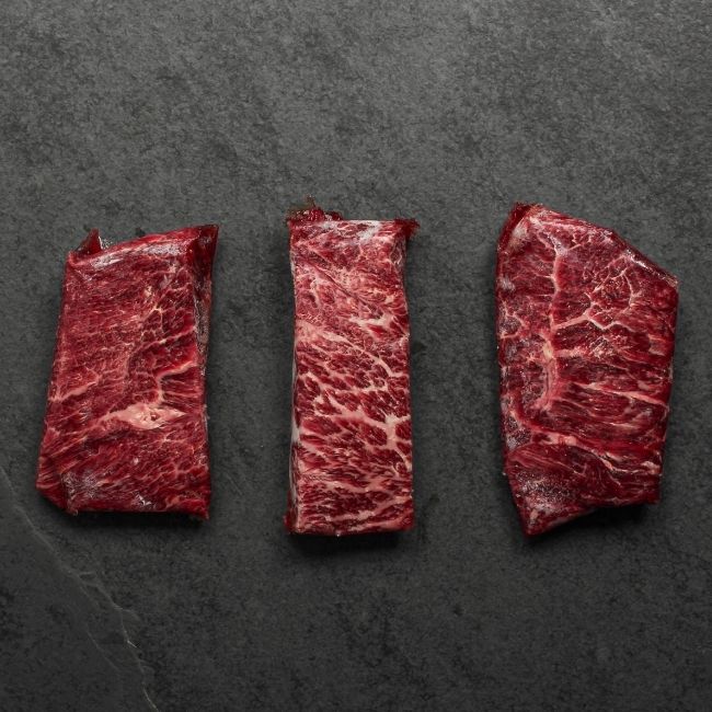 overhead view of three raw American wagyu beef flat iron steak random portions