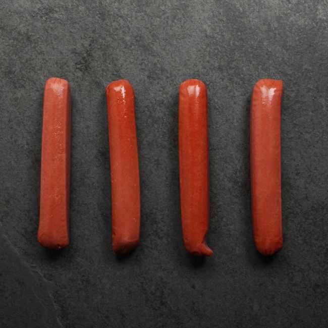 overhead view of four raw wagyu beef frankfurters