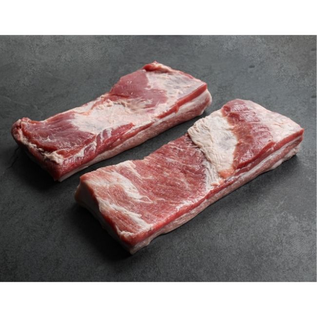 angled view of two raw pieces of skin-on pork belly