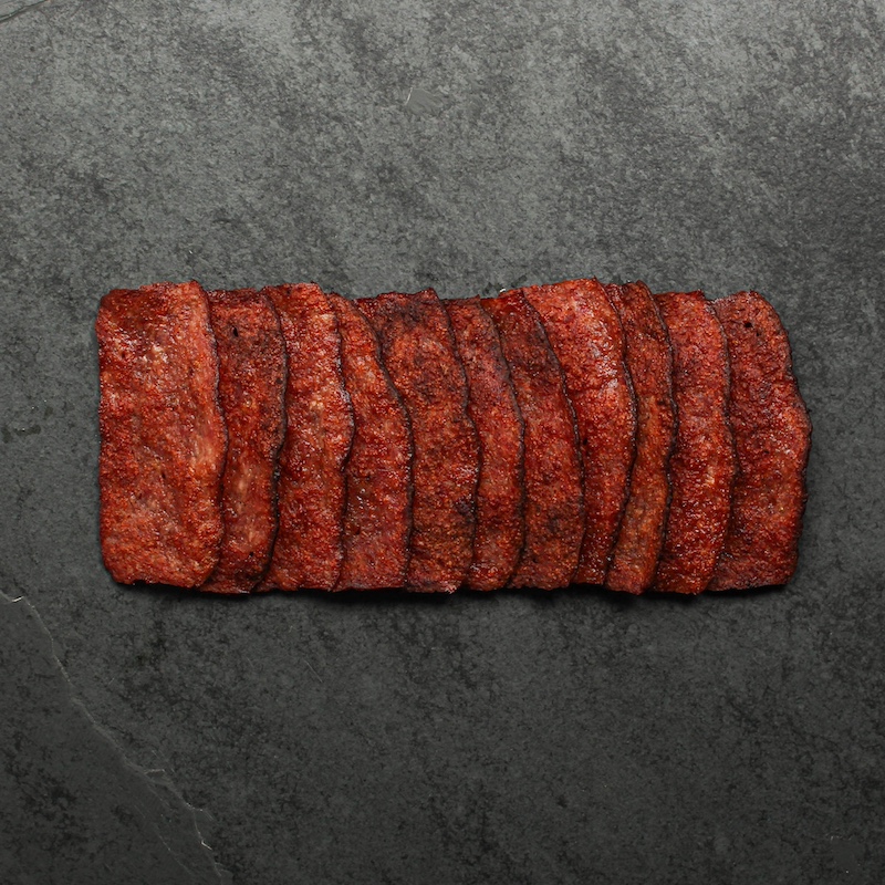 overhead view of cooked crispy turkey bacon splayed out on a piece of black slate