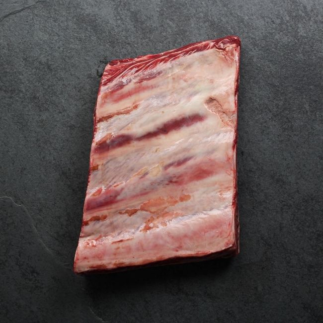overhead image of a piece of raw beef short ribs with 4 bones