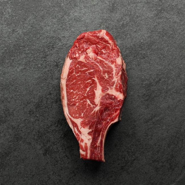 Bottom side of raw bone in rib steak.