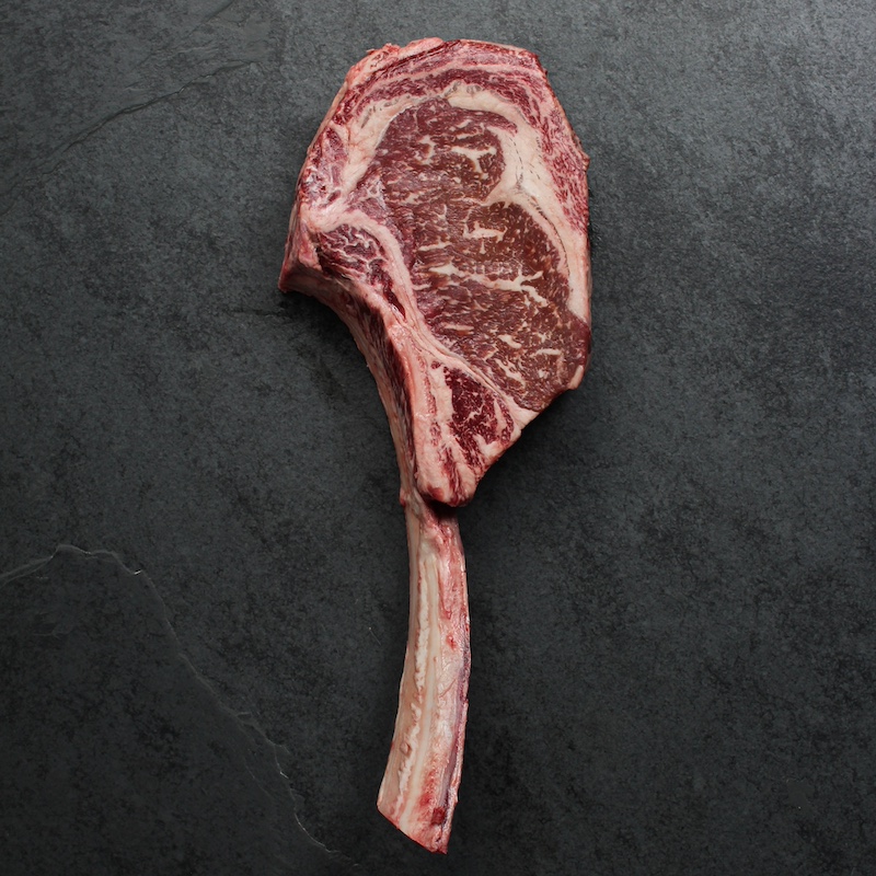 overhead view of a raw, richly-marbled wagyu beef tomahawk steak