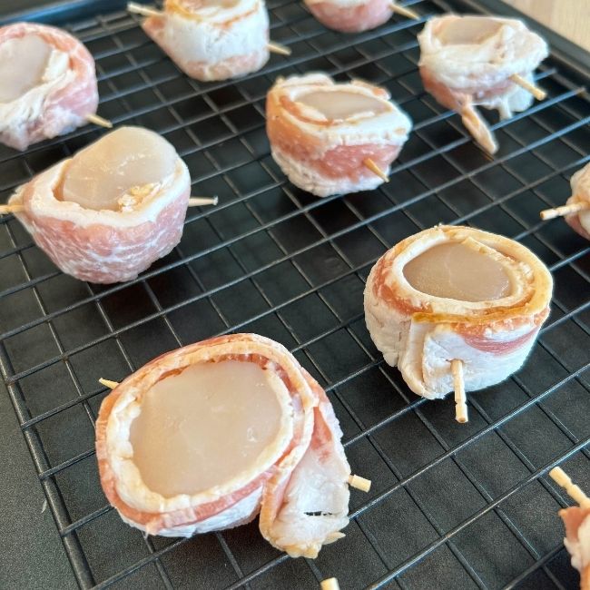 raw toothpick-skewed bacon-wrapped scallops on a wire rack-lined nonstick baking sheet