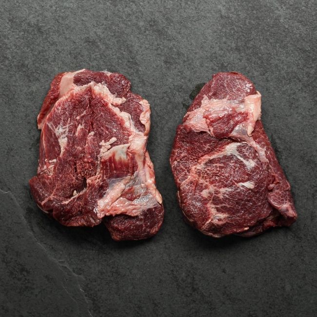 overhead view of two raw, richly-marbled beef cheeks