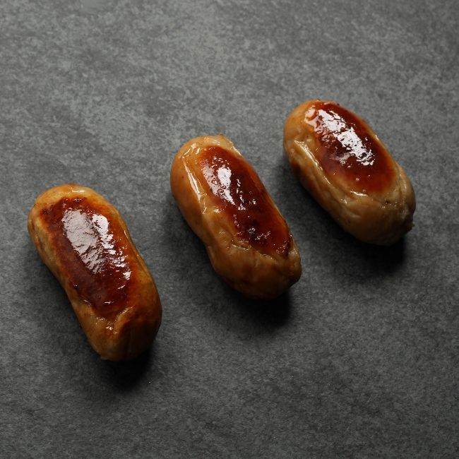 angled view of 3 cooked classic English breakfast banger sausages
