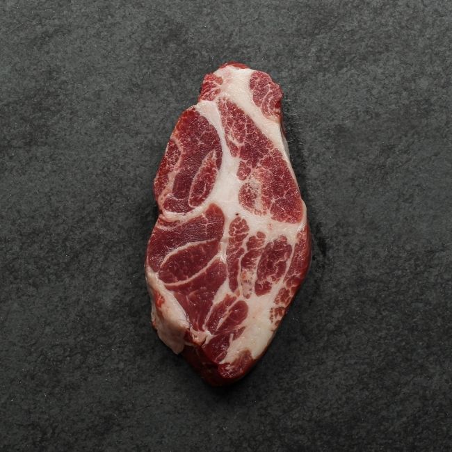overhead view of the underside of a heavily marbled iberico pork collar steak