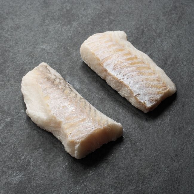 angled view of two pieces of raw haddock filets