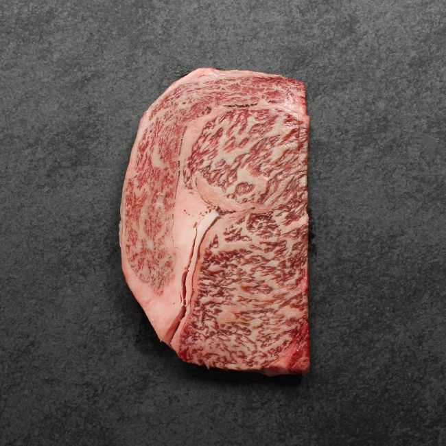 Bottom side of a heavily marbled wagyu rib eye steak.