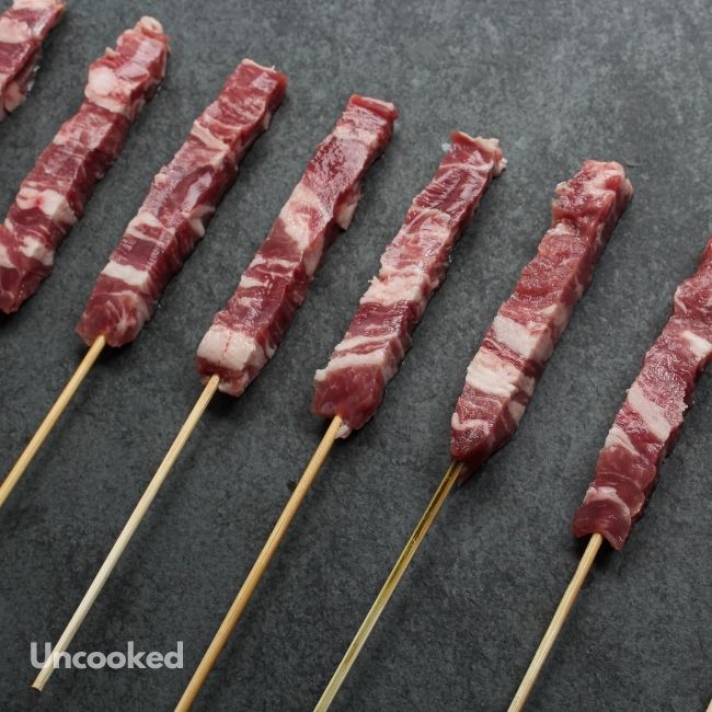 angled view of raw mini lamb skewers