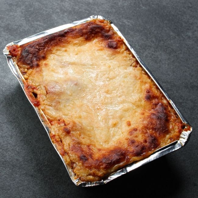 angled view of a cooked, cheesy lasagna with crispy edges