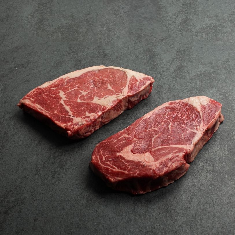 angled view of two raw rib eye steaks