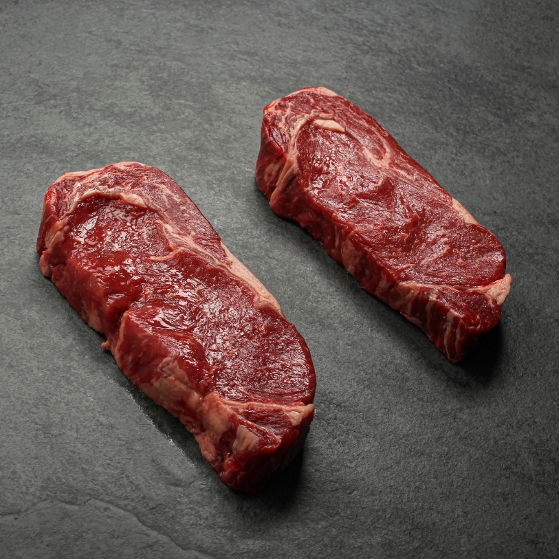 angled view of two raw Argentinian rib eye steaks