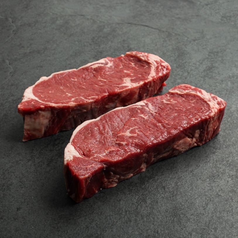 angled view of two raw new york steaks