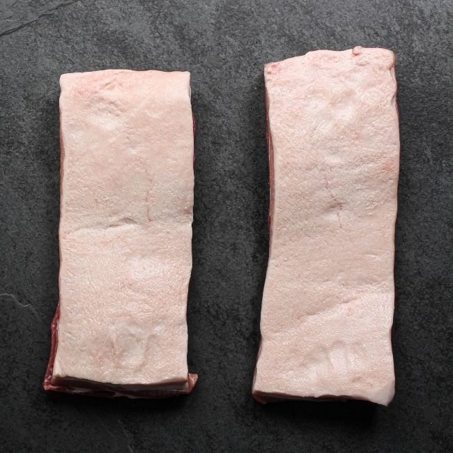 overhead view of two raw pieces of skin-on pork belly
