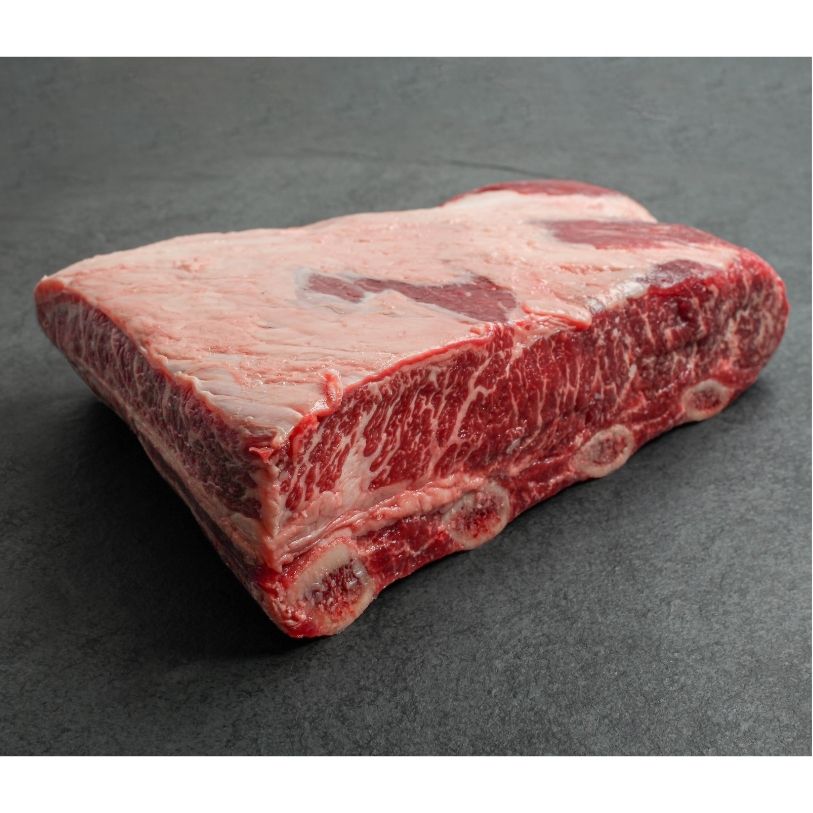 angled view of a piece of raw beef short ribs with 4 bones