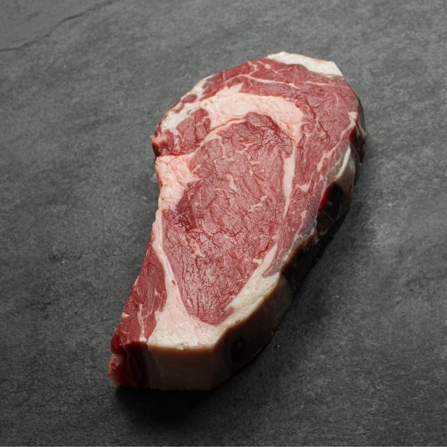 angled view of a raw dry aged rib eye steak