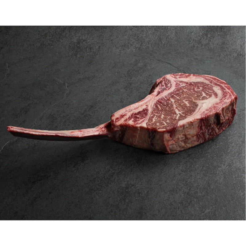 angled view of a raw, richly-marbled wagyu beef tomahawk steak