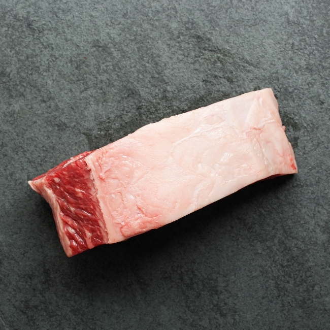Side view of a raw New York steak with the fat cap.