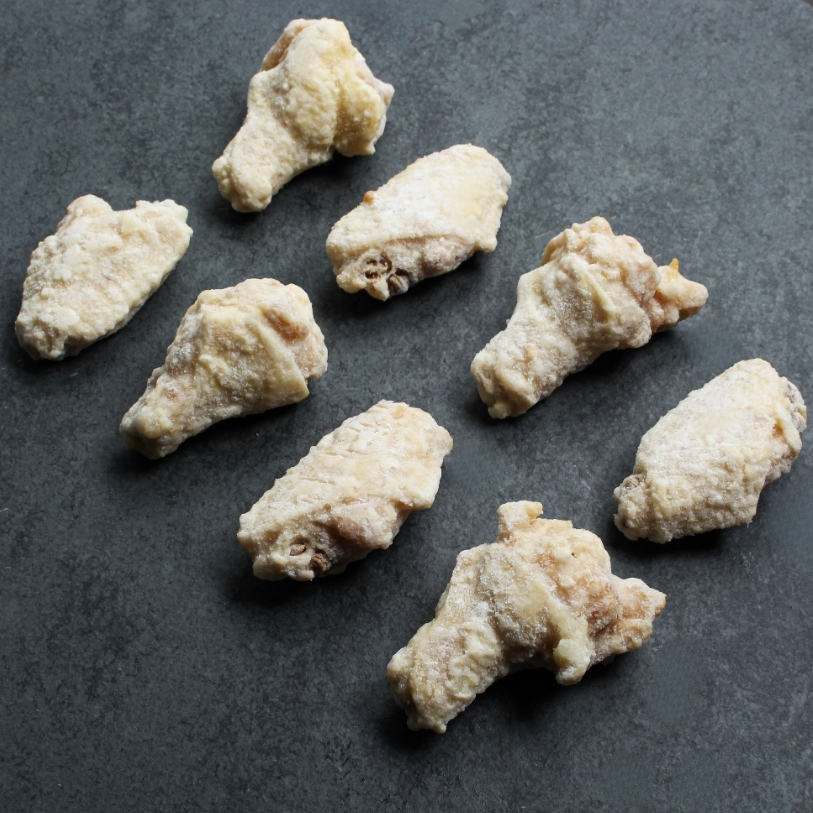 Angled overhead image of eight, frozen fully cooked chicken wings