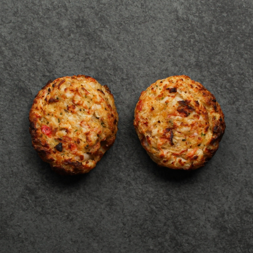 Overhead image of two cooked Seafood & Crab Cakes on a slate.