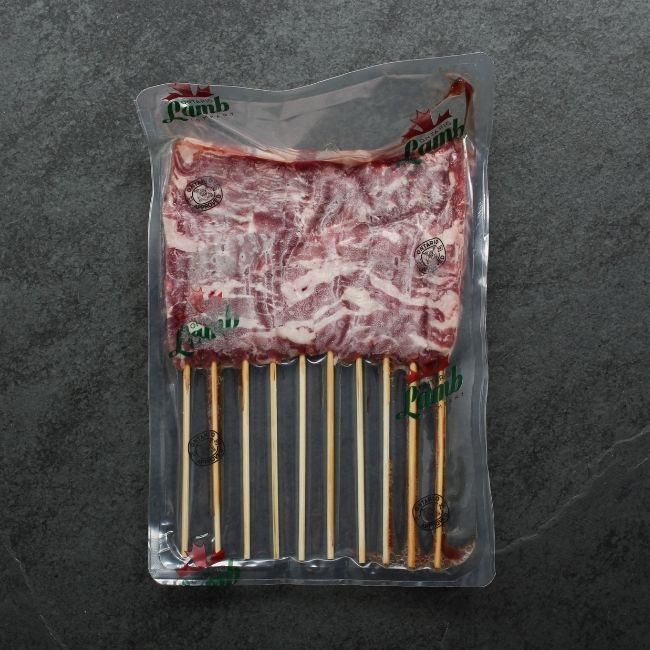overhead view of raw mini lamb skewers in a vacuum package