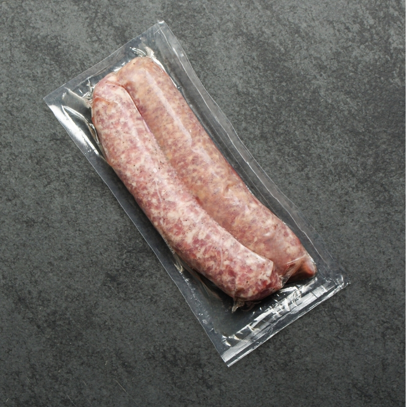 overhead shot of a raw mild Italian chicken sausage on black slate in vacuum sealed packagaing