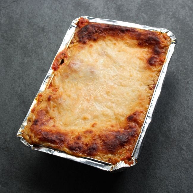 angled view of a cooked, cheesy lasagna with crispy edges