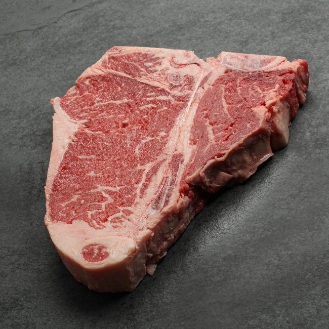 Angled view of a raw t-bone steak.