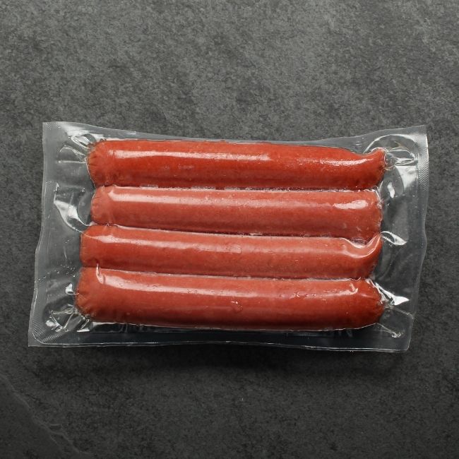 overhead view of four raw wagyu beef frankfurters in a vacuum package
