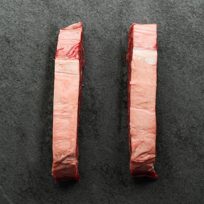 overhead view of the sides of two raw, heavily marbled Australian wagyu beef New York steaks